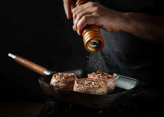 Gewürzmischungen: dieses Bild zeigt eine Person die ein Stück Fleisch mit Knoblauch-Pfeffer