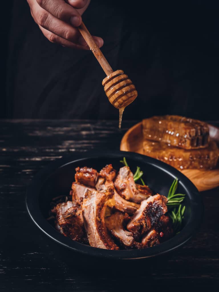 Barbecue ribs, cooked with a spicy basting sauce with honey on dark wooden background.